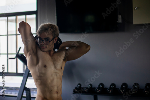Athletic shirtless handsome young man, muscular young men are exercising with weights in a gym.
