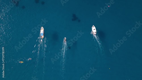 Trois bateaux naviguant côte à côte vus du ciel au-dessus d’une mer bleue