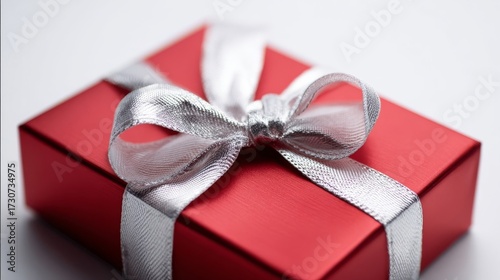 An elegant red gift box adorned with a shiny silver ribbon bow, symbolizing celebration, elegance, and festive joy.