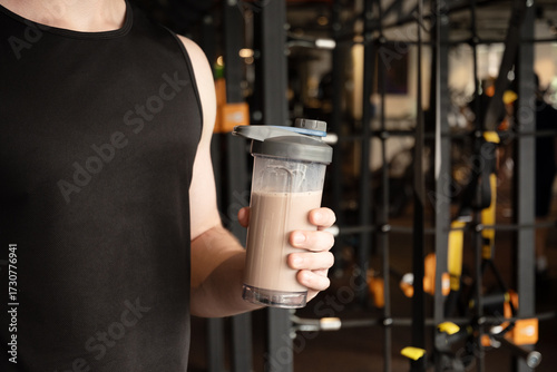 Protein shaker in man hand at gym or fitness center. Health care and workout. Close up.