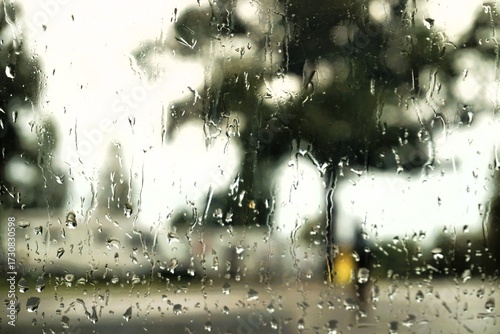 Abstraktes Motiv mit Regentropfenmuster vor Wohnmobilstellplatz, hohen Bäumen, Mutter mit Kind in gelbem Regenmantel und weißem Himmel mit Licht bei Regen und Sturm im Herbst