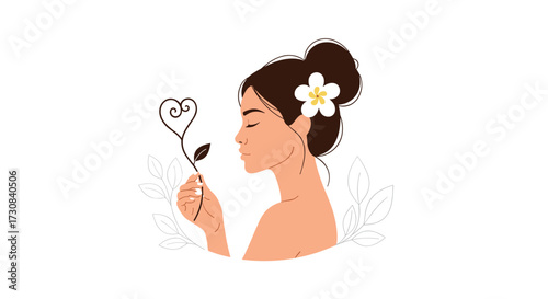 A serene woman with her hair in a bun delicately holds a flower stem forming a heart shape near her nose.