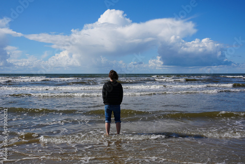 Ein junger Mann steht mit den Füssen in der Nordsee am  Strand Lakolk auf der Insel Rømø in Dänemark