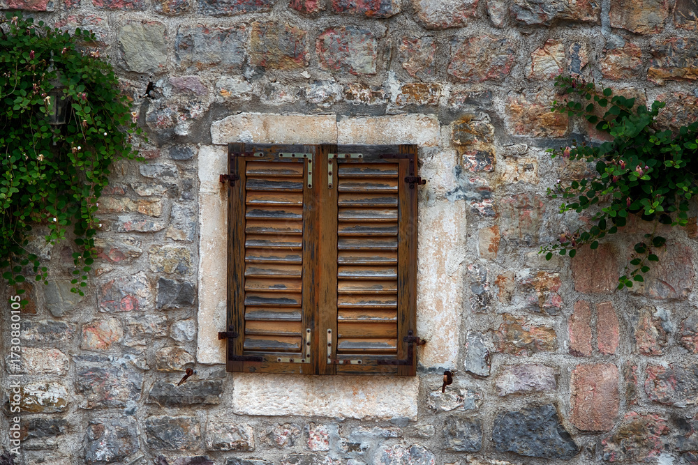 Fototapeta premium Window Covered with Wooden Shutters on Old Stone House