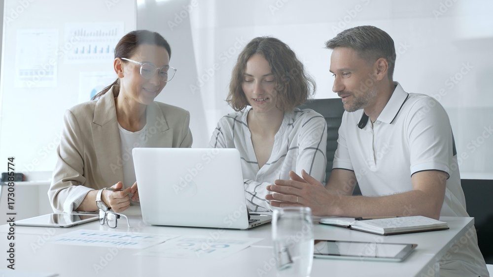 Fototapeta premium Business professionals reviewing marketing analytics on laptops, working together strategically in contemporary workplace with minimalist interior design and collaborative atmosphere