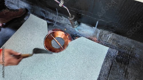 Roofer applying torch to bitumen membrane on torch down roof