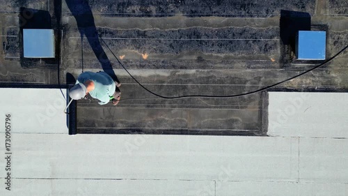 Roofer applying torch to bitumen membrane on torch down roof