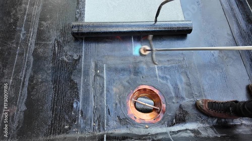 Roofer applying torch to bitumen membrane on torch down roof