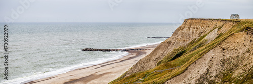 The coast stretches endlessly, soft grass leading to hard cliff edges. The lighthouse listens, steadfast, as the North Sea sings its eternal song. Denmark, 2025.
