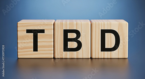 Wooden blocks spelling tbd to be determined concept on a blue background for business and planning 100