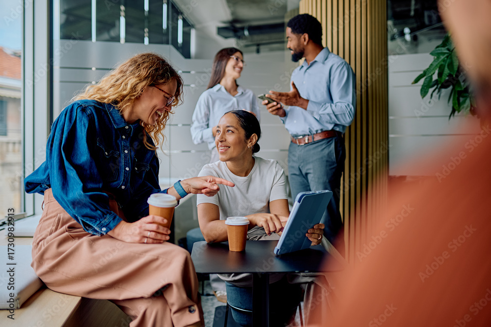 Obraz premium Diverse colleagues discussing ideas and smiling during a coffee break in a modern office, enjoying teamwork and informal interaction