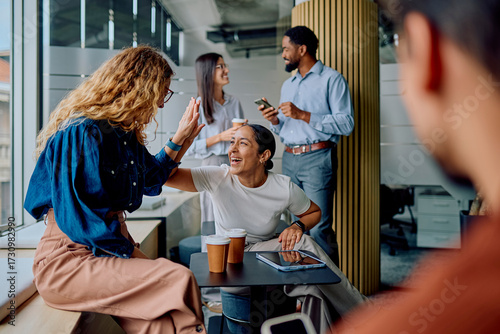 Foto Diverse business colleagues high-fiving, smiling, and discussing in a modern off