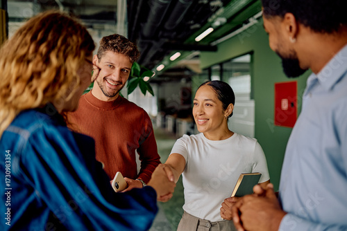 Diverse business people handshaking, smiling in a modern office, symbolizing partnership, collaboration, and successful meeting in a corporate environment