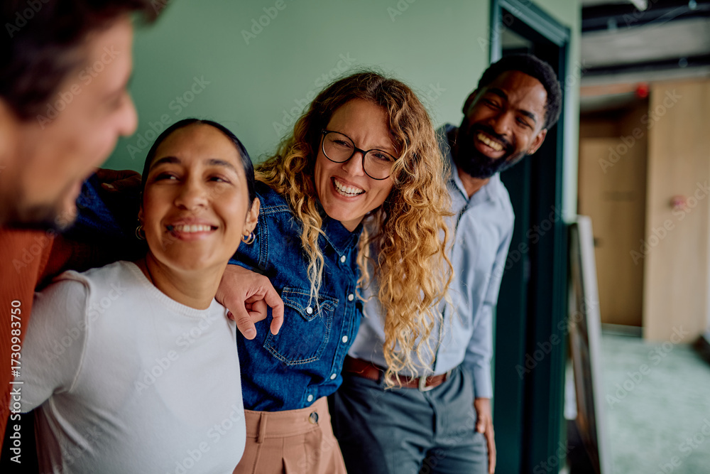 Fototapeta premium Diverse business friends smiling and laughing together, demonstrating camaraderie and positive teamwork in an office environment