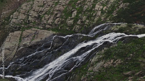 A mountain waterfall, streams of pure water falling down from a sheer cliff, flowing over moss and stones, the beauty and power of nature