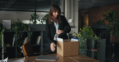 Young professional woman in business attire unpacks a moving box with office supplies during onboarding in a bright modern office symbolizing a fresh start and new career