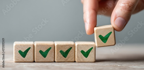A hand places a small wooden block with a green check mark on top of a row of similar blocks