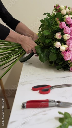 florist wraps a bouquet with ribbon