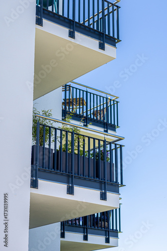 Balconies with plants under a clear blue sky in an urban area showcasing modern architecture design