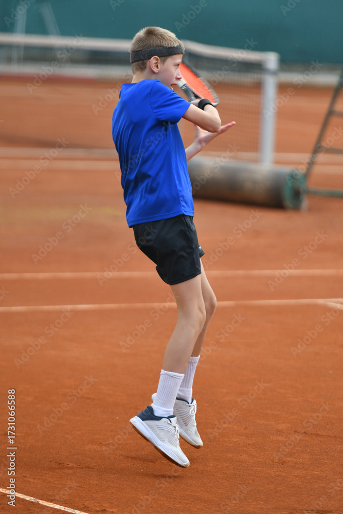 Obraz premium Young boy playing tennis on real court outdoor
