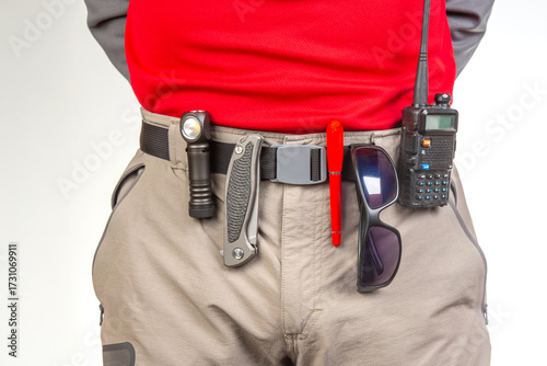Explorer gears up for adventure with essential tools at their waist in bright light