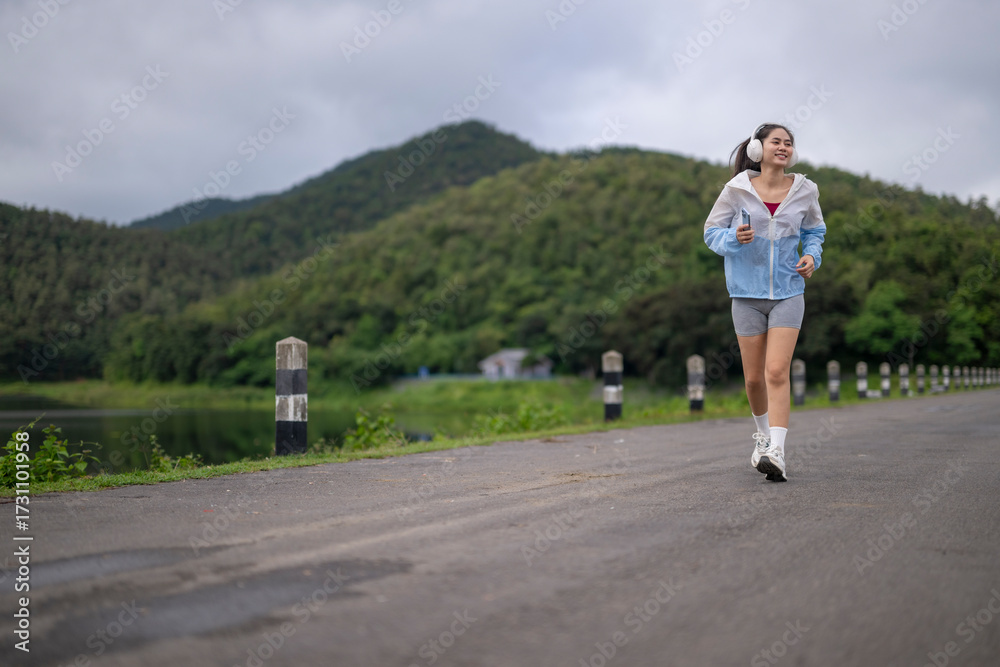 Obraz premium Young woman running outdoors in nature with headphones