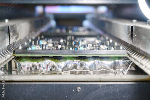 Billede på lærred Wave soldering process for PCB tinning in a molten solder bath showcasing intric