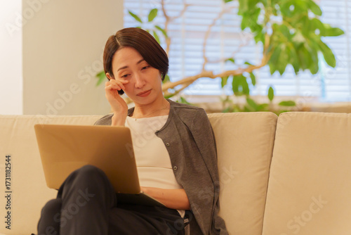 夜パソコンで仕事する眼精疲労の女性