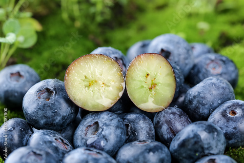 Foto Fresh Alpine Blueberries Cut in Half Showing White Pulp on Green Moss Background