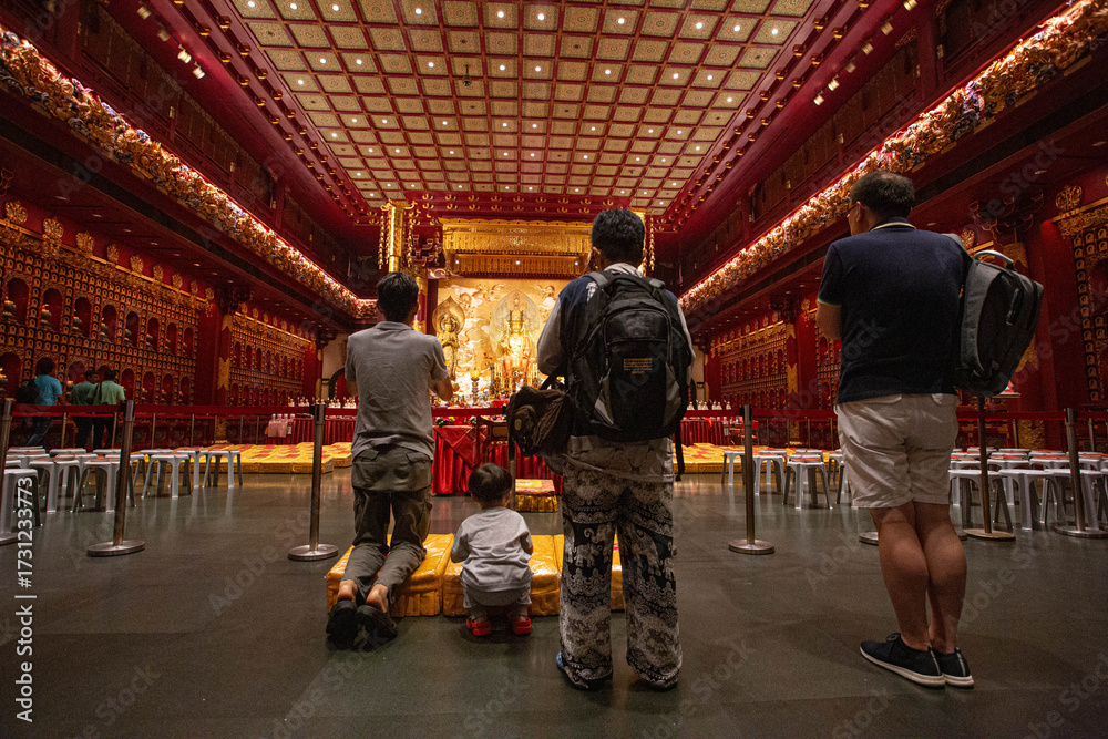 Naklejka premium On September 24, 2018, inside a grand temple in Singapore, the main hall glows with golden Buddha statues, ornate decorations and rows of offerings, embodying devotion, peace, and sacred spirituality.