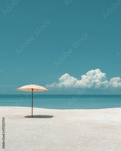 Solitary beige beach umbrella on pristine white sand, tranquil turquoise ocean and clear blue sky with fluffy clouds