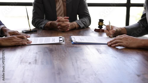 Lawyers mediating and signing a contract after a successful negotiation, reaching a compromise on a wooden table with a gavel.