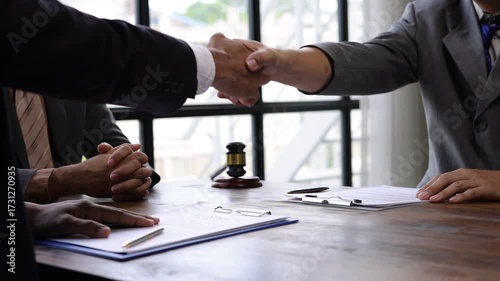 Professional lawyers sealing successful partnership through firm handshake after signing legal contract in corporate office, representing collaborative business agreement.