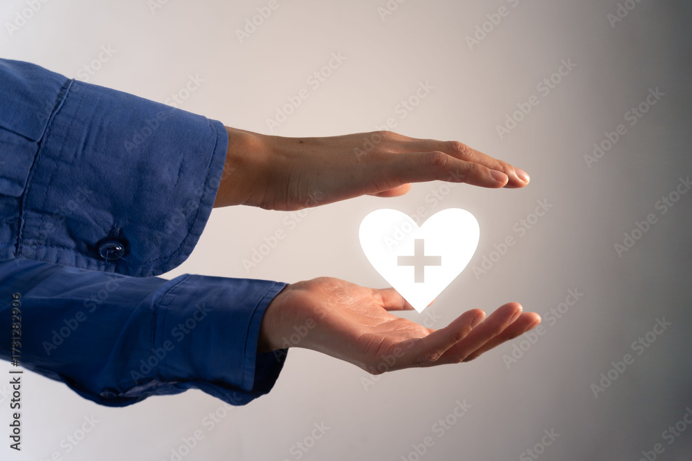 Fototapeta premium Heart with a health sign in the middle held between a pair of hands