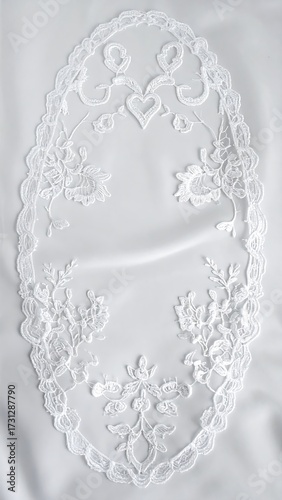 Oval white lace doily on fabric, delicate floral and heart motifs