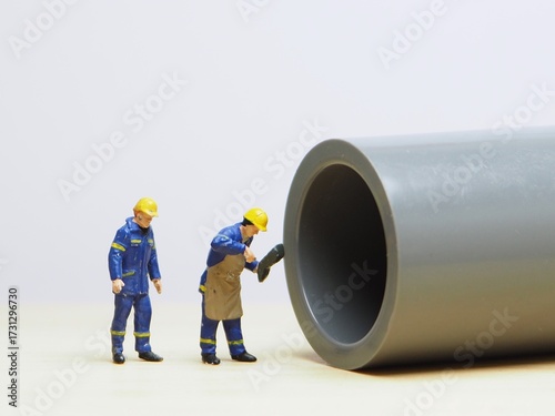 Mini toy of action figure at table with blurred background. Industrial photography concept design. Minifigure of worker character at outdoor pipe tunnel.