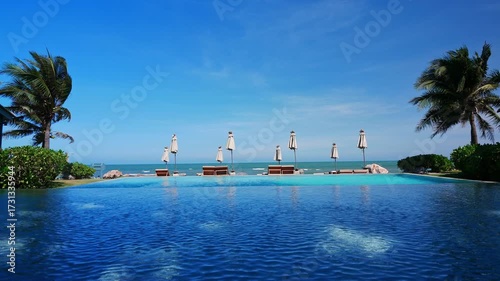 Swimming pool with umbrella and chair on sea view background
