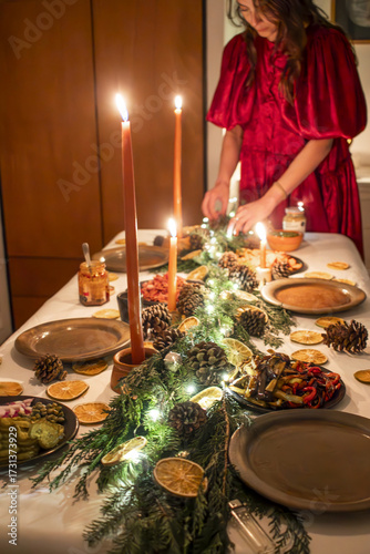 Woman in Red Dress Setting Festive Christmas Dinner Table with Garland
