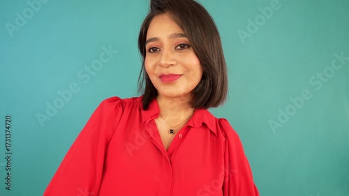 Portrait closeup of happy smiling confident beautiful young Indian woman girl looking at camera feels happiness joy, isolated over blue background.