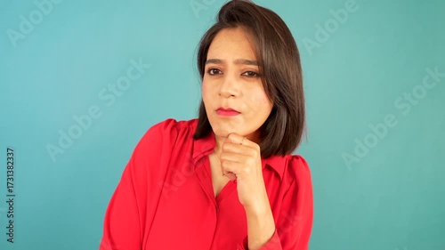 Closeup of thoughtful confused young woman thinking pondering future decisions unsure choice looking at camera with doubtful face expression, isolated over blue background. 