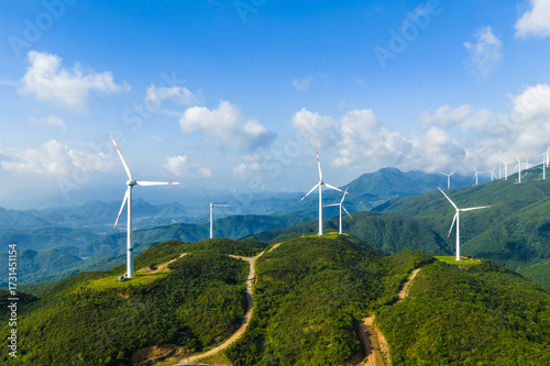Aerial view of wind turbines on the green mountain generating clean and renewable energy on a sunny day