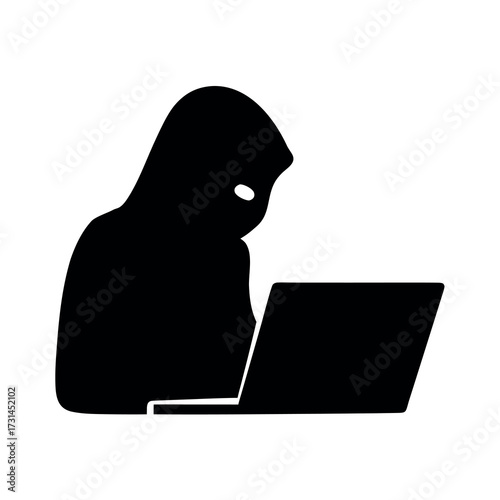 Silhouette of a hooded figure working on a laptop computer in the dark