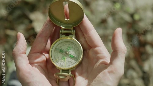 Man explorer searching direction with compass in summer mountains, point of view. compass for orienteering, hand holds magnetic compass, hike in the mountains, trekking alone, survival in the forest.