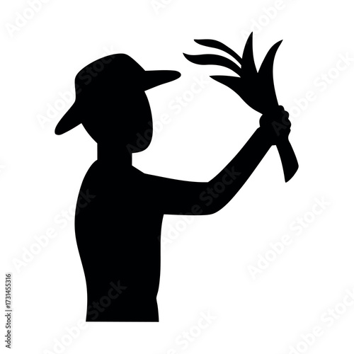 Silhouette of a farmer wearing a hat holding a bunch of harvested crops