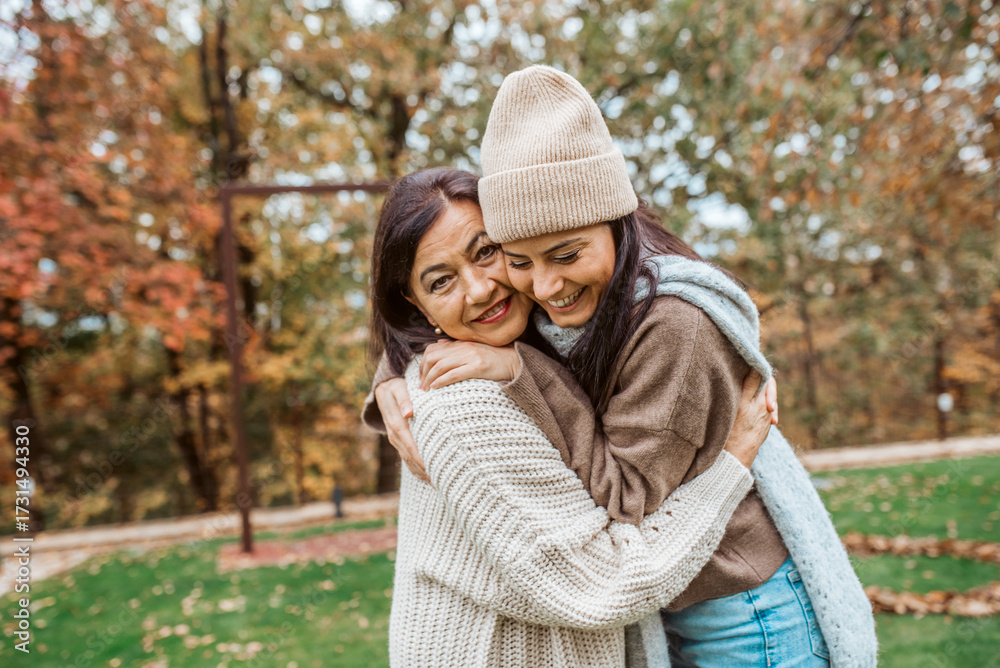 Fototapeta premium Mature daughter with older mom embracing in autumn park. Mother's day concept.