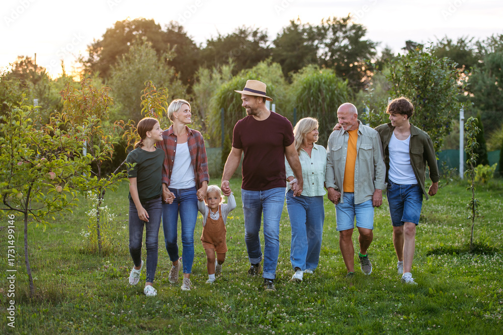 Obraz premium Multigenerational family outdoors, on walk, holding hands.