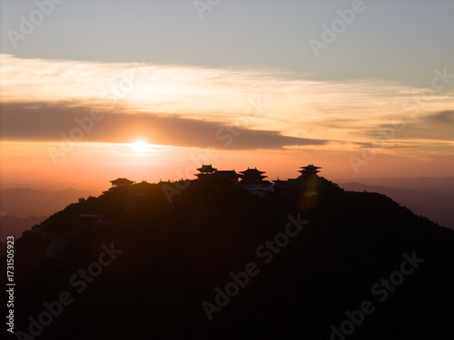 Dahong Mountain silhouette against a sunset sky in Suizhou, China, with buildings crowning the peak and the sun low on the horizon.