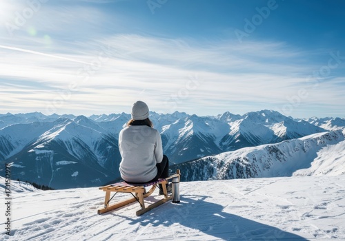 Woman sitting on a sled on a snowy mountain with a view of the alps