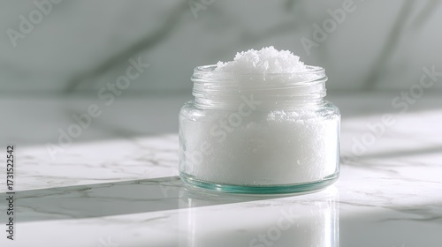 White Mineral Salt in Glass Jar on Marble Background