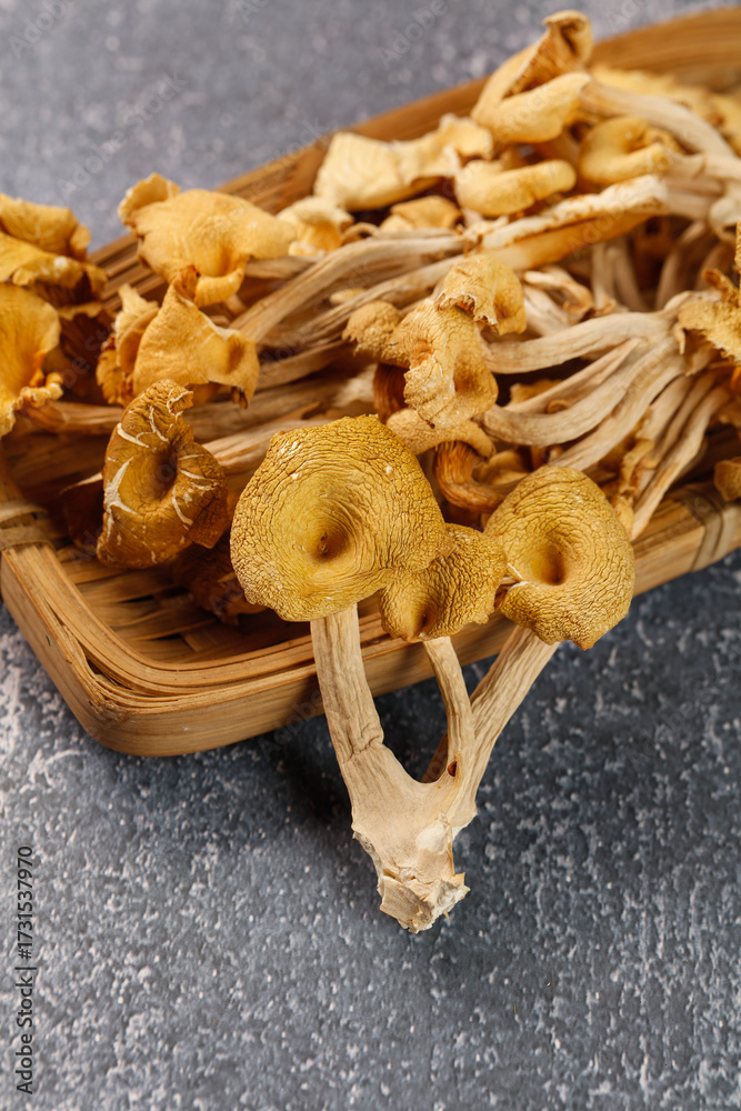 Fototapeta premium Dried Golden Chanterelle Mushrooms from Yunnan China in Wooden Basket on Stone Surface